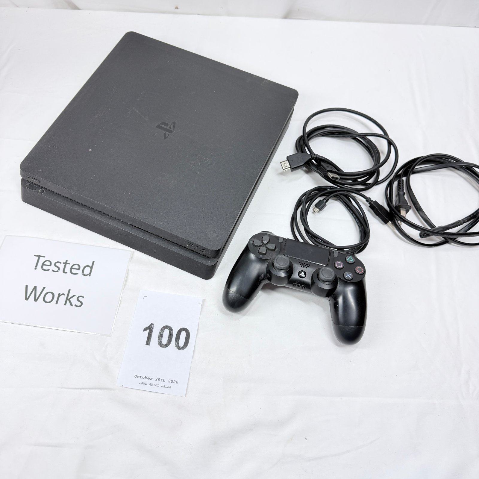 Lot 100: Sony PlayStation 4 Slim console with DualShock 4 controller, HDMI and power cables, tested working