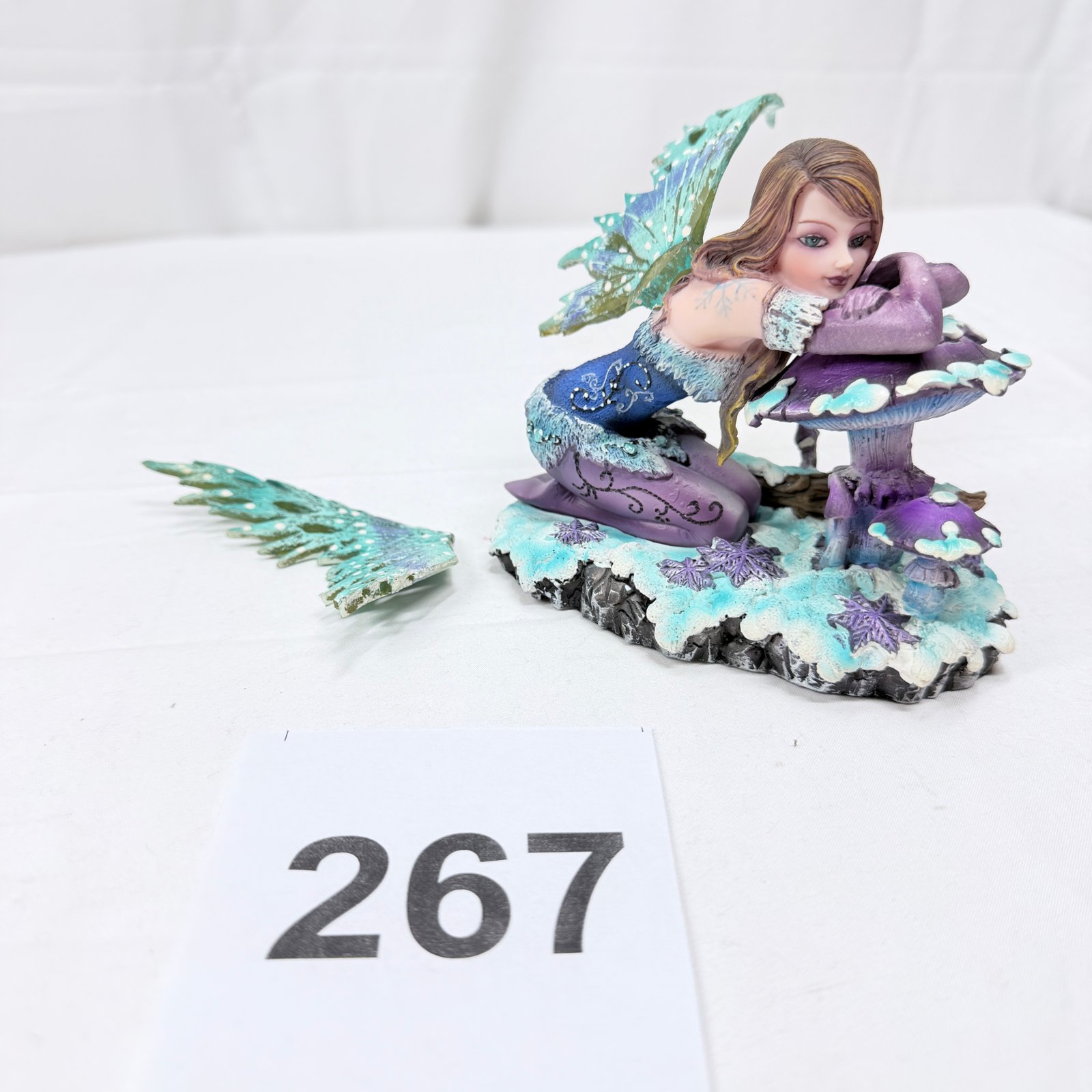 Lot 267: Winter fairy figurine, resin, kneeling on mushroom with snowflake base (AS IS, wing broken off)