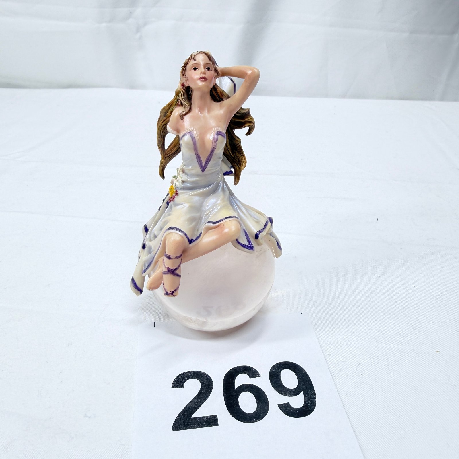 Lot 269: Figurine of maiden seated on frosted glass ball, flowing gown with floral hair accents