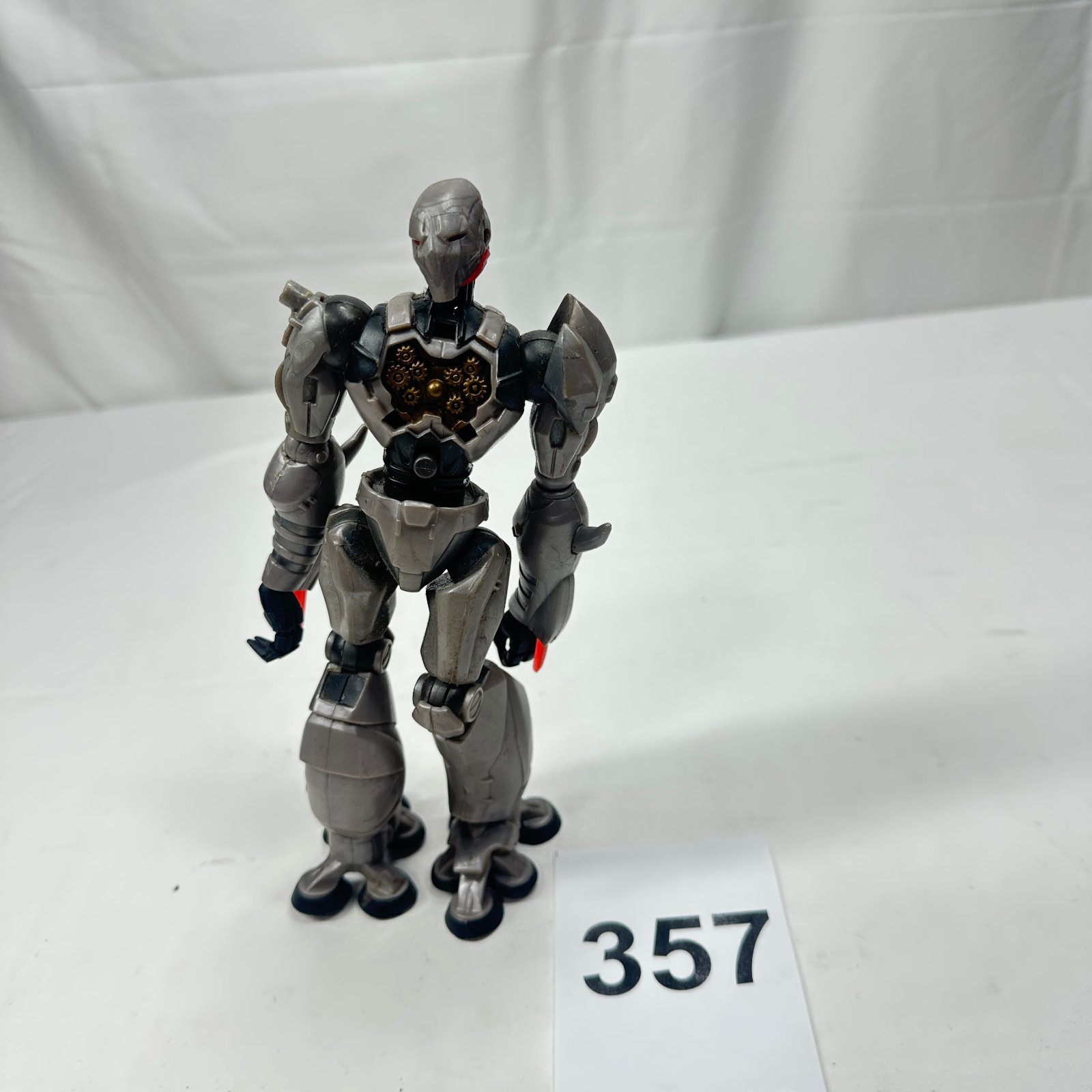 Lot 357: Steampunk-style gray robot action figure with gear-detail chest plate and dual multi-barrel shoulder cannons