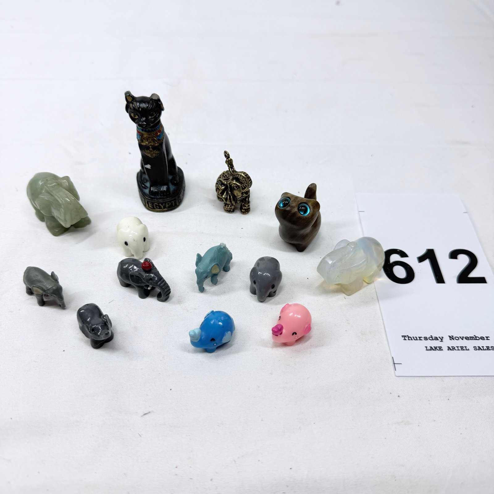 Lot 612: Mixed carved stone and resin elephant figurine collection with Egyptian Bastet cat statue, jade/opalite elephants and miniature animal figures, 13 pieces