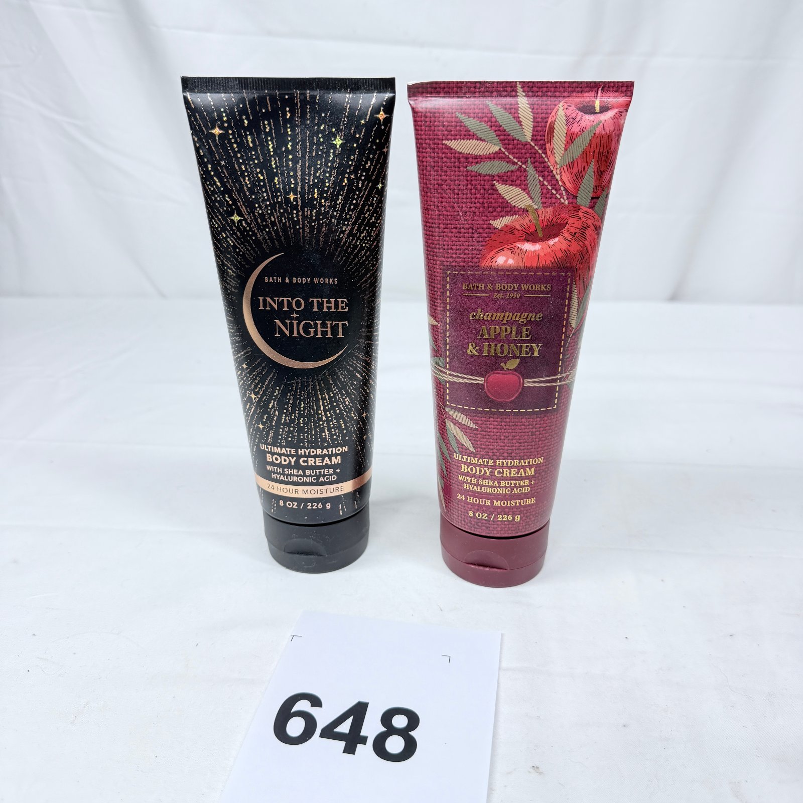 Lot 648: Bath & Body Works "Into the Night" & "Champagne Apple & Honey" Ultimate Hydration Body Cream set, 8oz each