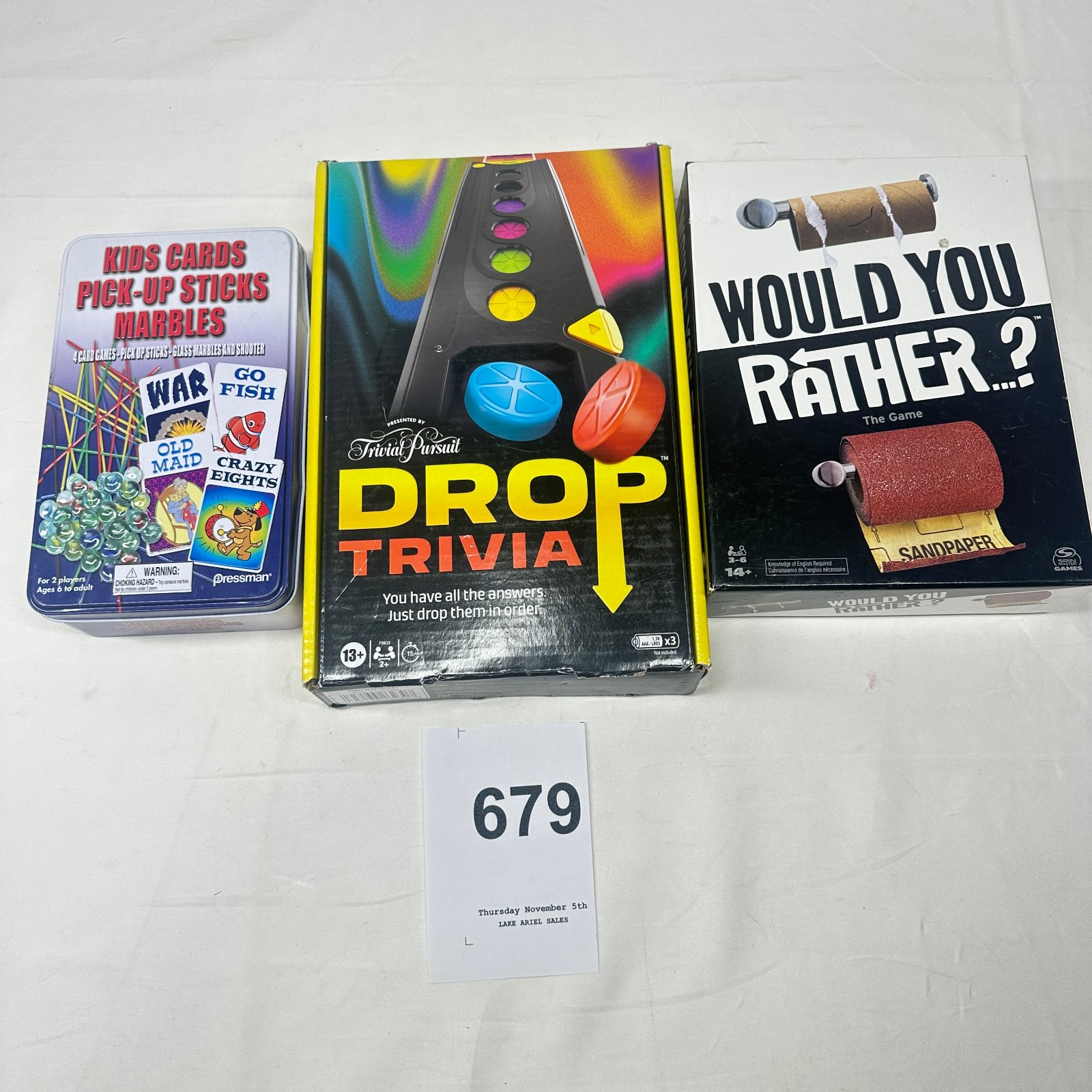 Lot 679: Board game lot: Pressman Kids Cards/Pick-Up Sticks/Marbles tin, Hasbro Trivial Pursuit "Drop Trivia," Spin Master "Would You Rather...?