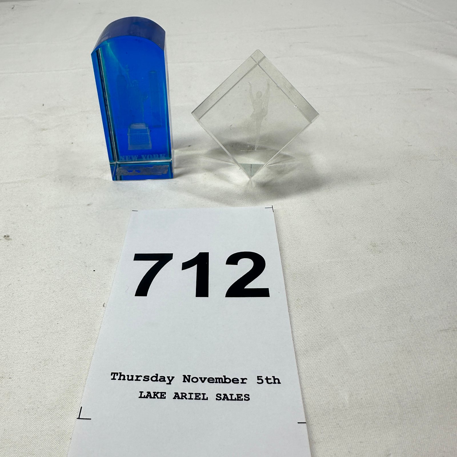 Lot 712: 3D laser-engraved crystal set: blue New York skyline block with Statue of Liberty, Empire State Building, Freedom Tower, and clear pyramid ballerina paperweight
