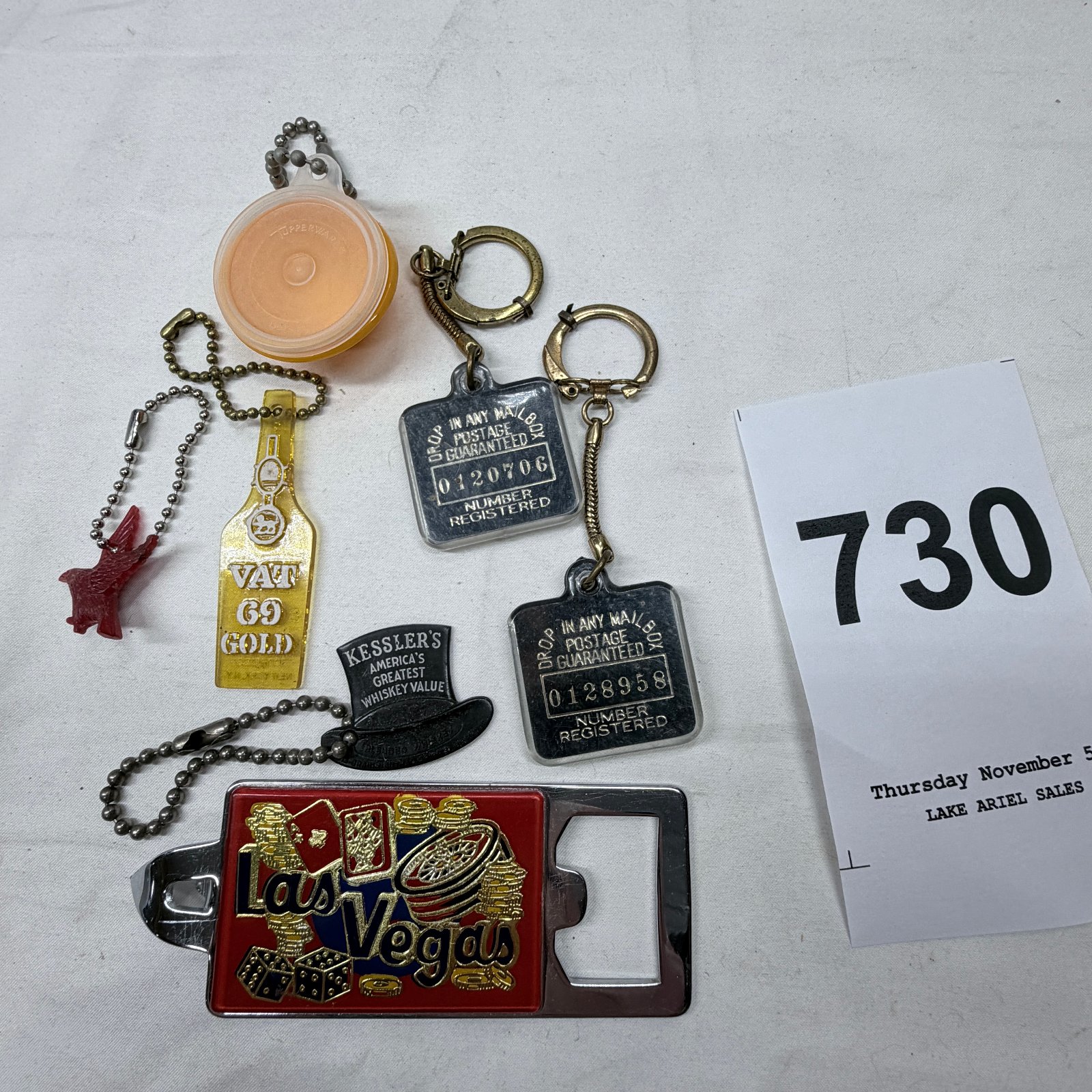 Lot 730: Mixed advertising keychain lot: VAT 69 Gold, Kessler's Whiskey, Las Vegas bottle opener, Tupperware fob & mailbox return tags