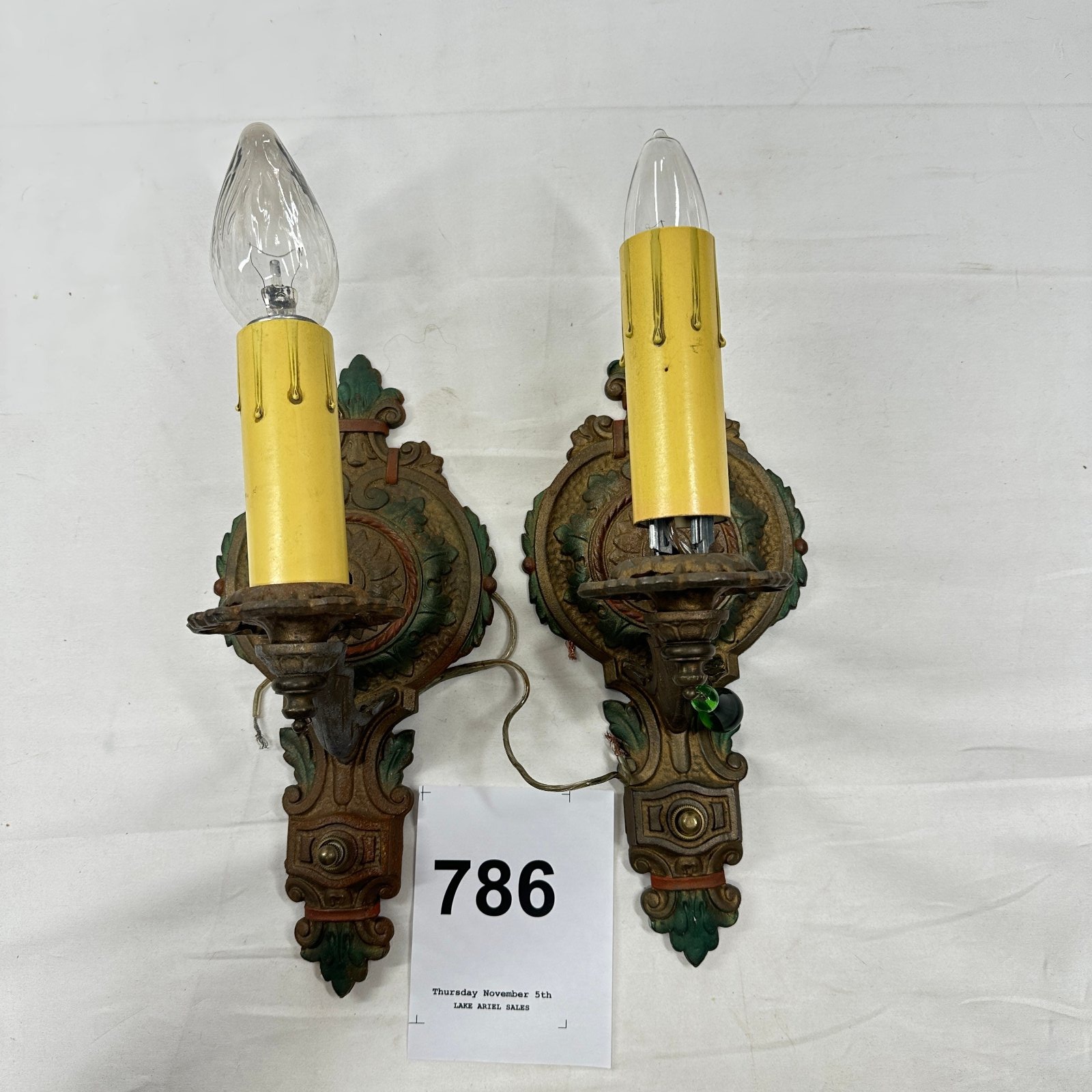 Lot 786: 1920s cast iron wall sconces, pair with polychrome floral motif and candle-flame bulbs, Art Deco figural lighting
