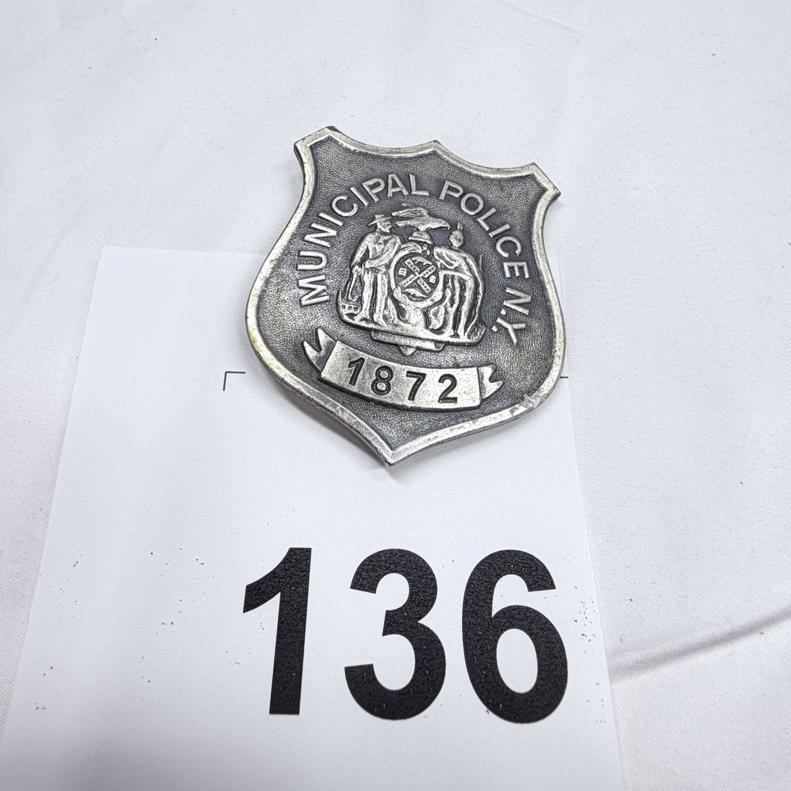 Lot 136: Reproduction Municipal Police N.Y. 1872 shield badge, silver-tone souvenir replica