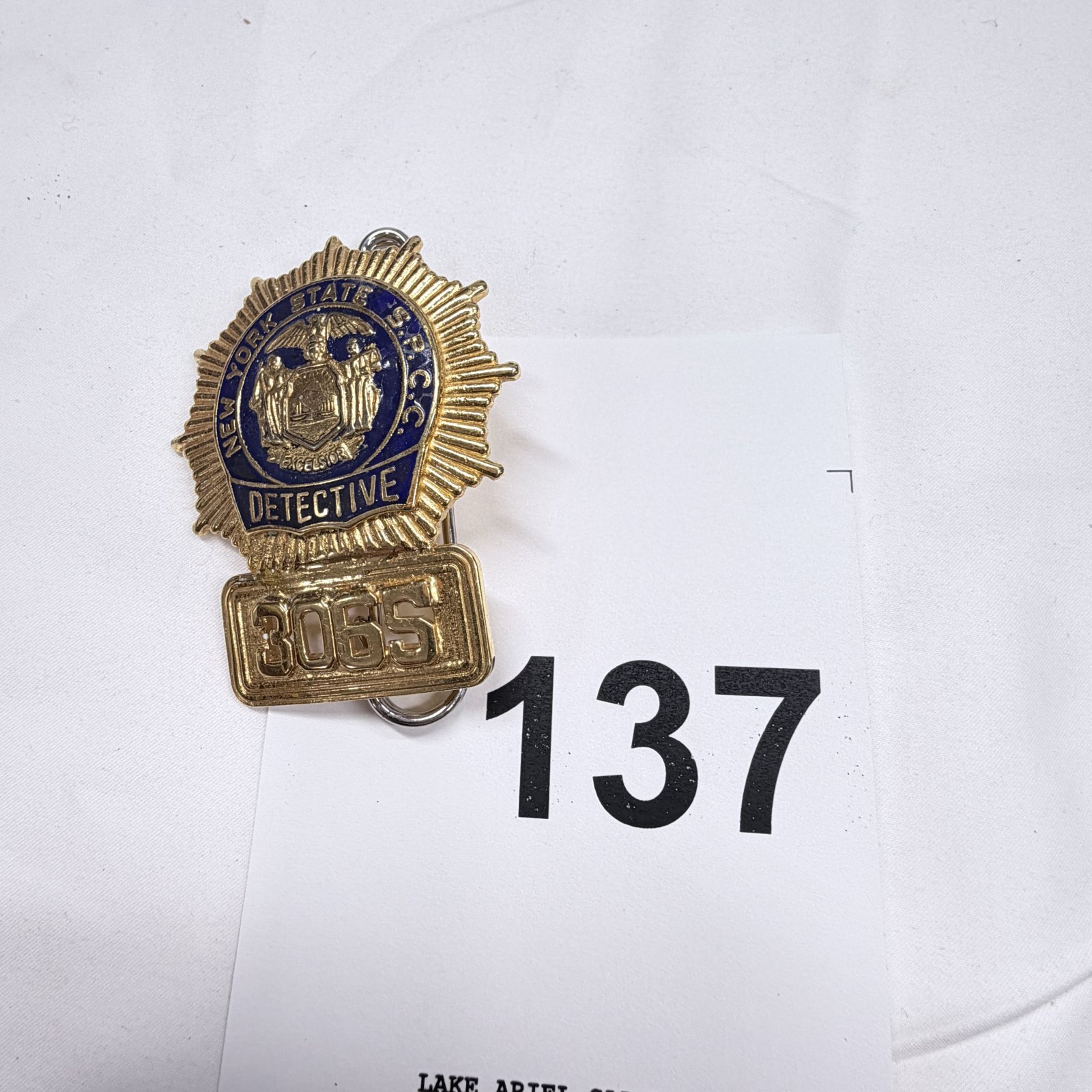 Lot 137: New York State S.P.C.C. "Detective" badge #3065, gold-tone shield with New York State seal, safety-pin back