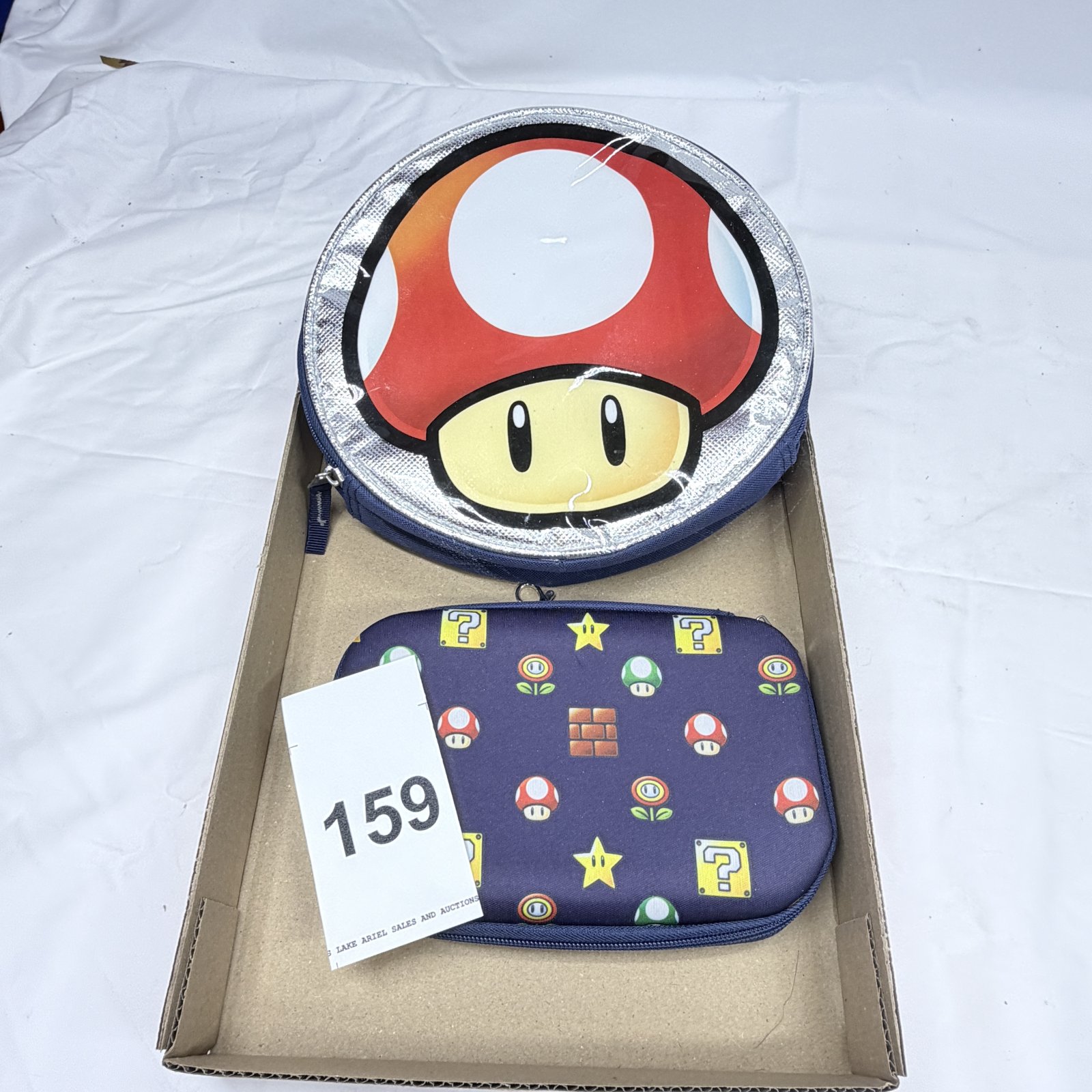 Lot 159: Super Mario Bros. Nintendo carrying case set - round Toad zip case & 3DS/2DS hard case, Mushroom Kingdom icons