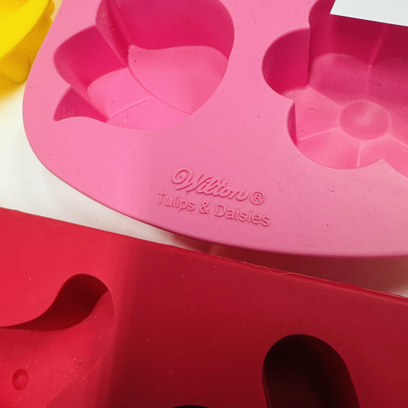 Lot 416: Wilton silicone bakeware lot: "Tulips & Daisies" flower molds, gingerbread man molds, and deviled egg trays, 7 pieces